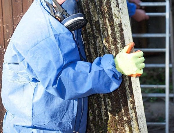 Asbestos corrugated roofing sheet being removed and sealed in a plastic sheet